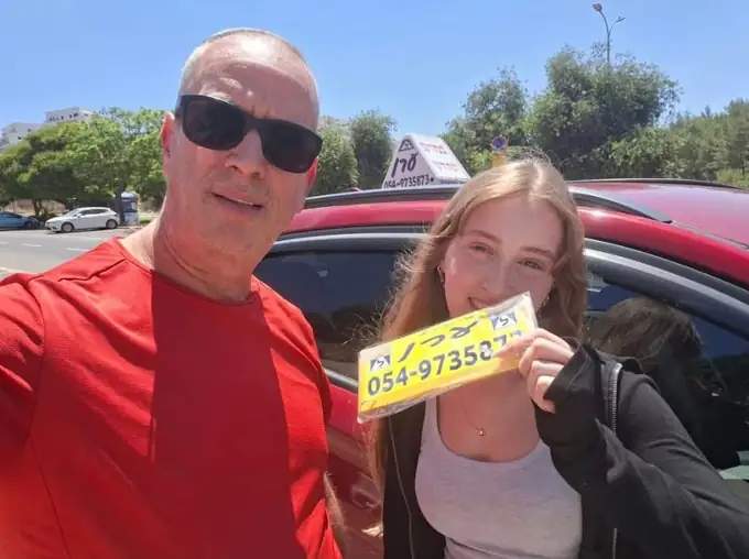 תלמידה של ערן הרשקוביץ חוגגת מעבר טסט נהיגה ליד רכב הלימוד