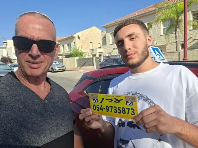 ערן הרשקוביץ, מורה נהיגה באריאל, עם תלמיד שעבר טסט ומחזיק את שלט הלמידה
