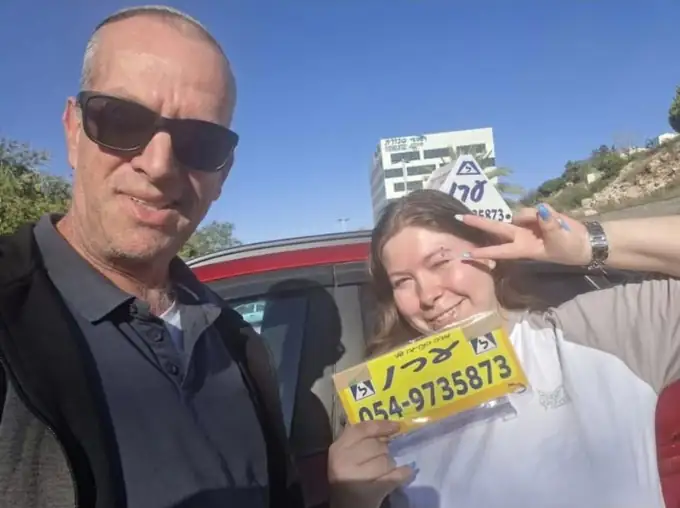תלמידה מחזיקה את שלט הלמידה של ערן אחרי שעברה טסט נהיגה