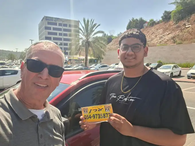 תלמיד עם שלט הלמידה של ערן הרשקוביץ, מורה נהיגה באריאל